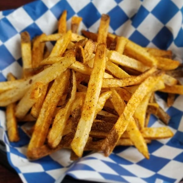 Seasoned fries in a blue and white checkered paper liner, from Big Ray's Burgers & Dogs.